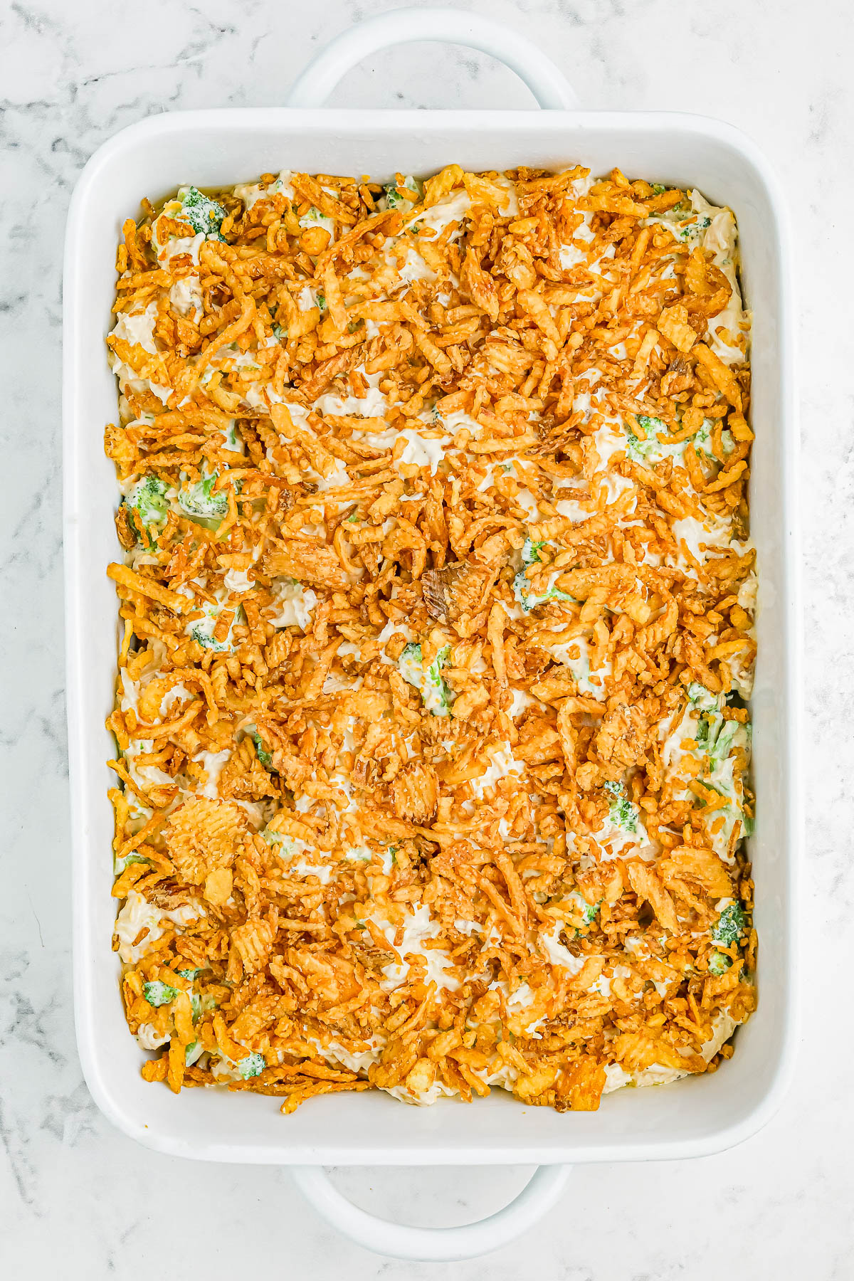 A casserole dish filled with a baked dish topped with crispy, golden-brown fried onions on a creamy base with visible vegetable pieces.