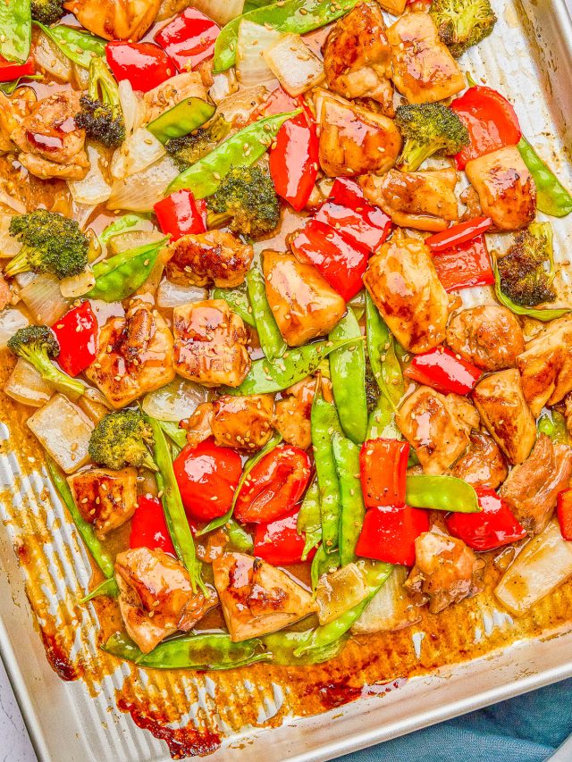 Sheet pan dish with glazed chicken pieces, red bell peppers, broccoli, snow peas, and onions.