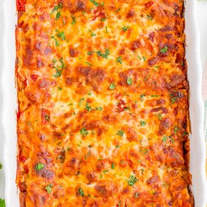 A baked casserole dish filled with golden-brown, cheesy lasagna topped with chopped herbs.