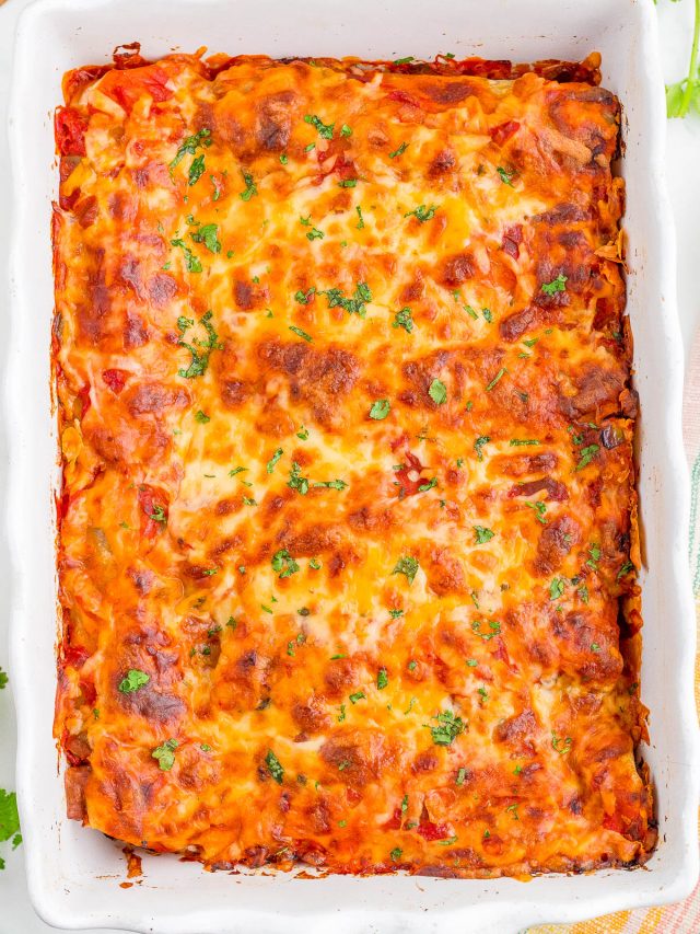 A baked casserole dish filled with golden-brown, cheesy lasagna topped with chopped herbs.