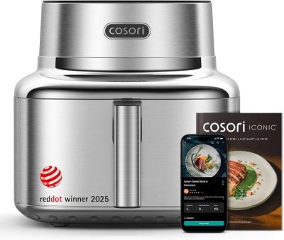 A stainless steel Cosori air fryer with a Red Dot Winner 2025 label, shown with a recipe booklet and a smartphone displaying a cooking app.