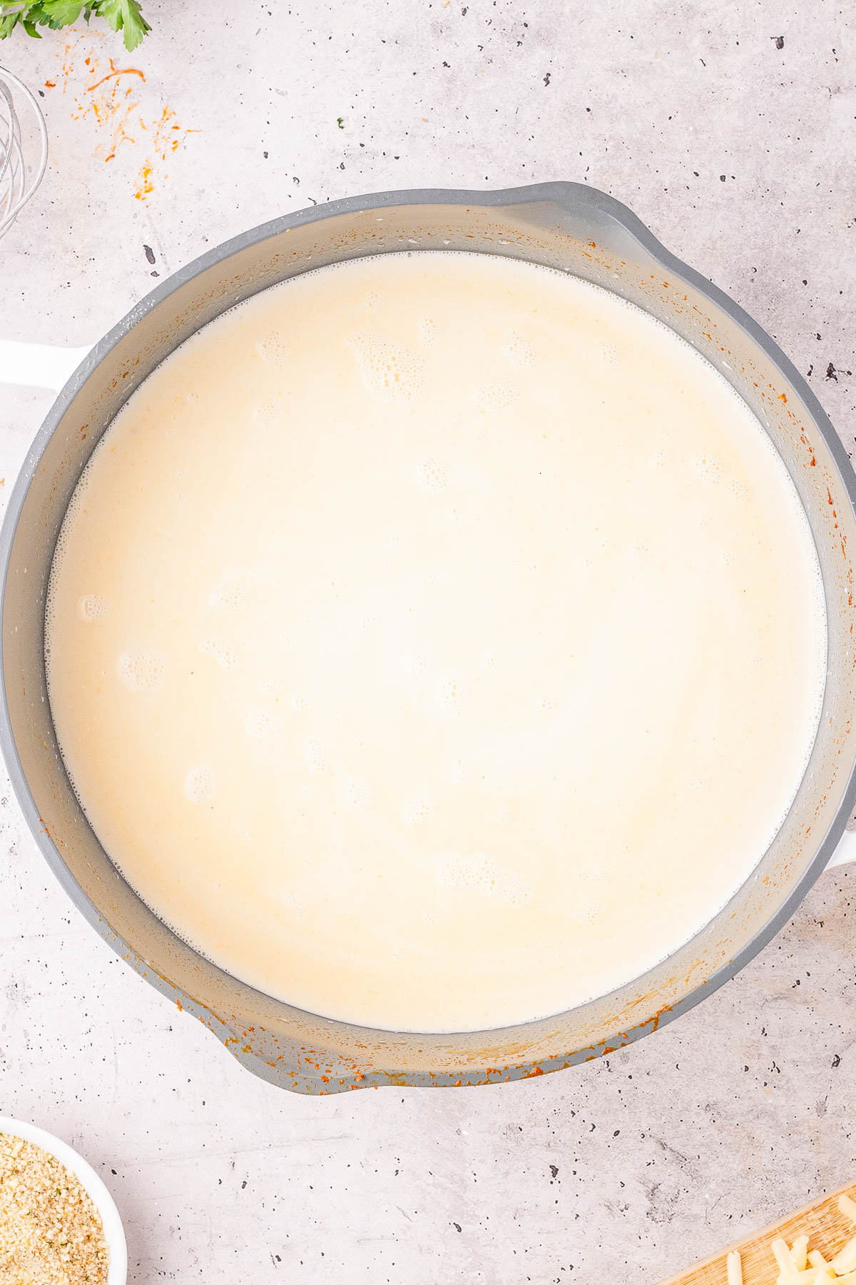 A large pot filled with creamy white sauce sits on a light-colored countertop.