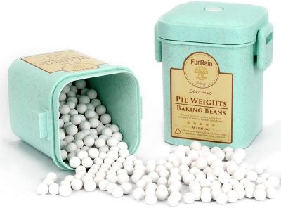 Two light green containers labeled "Pie Weights Baking Beans" with white ceramic balls, some spilling out onto the surface.