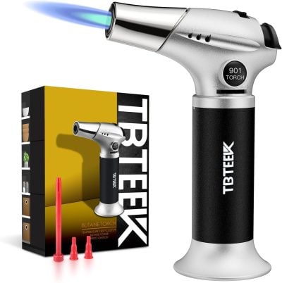 A butane torch with a blue flame, three red nozzle attachments, and a branded box labeled TBTEEK displayed next to the torch.