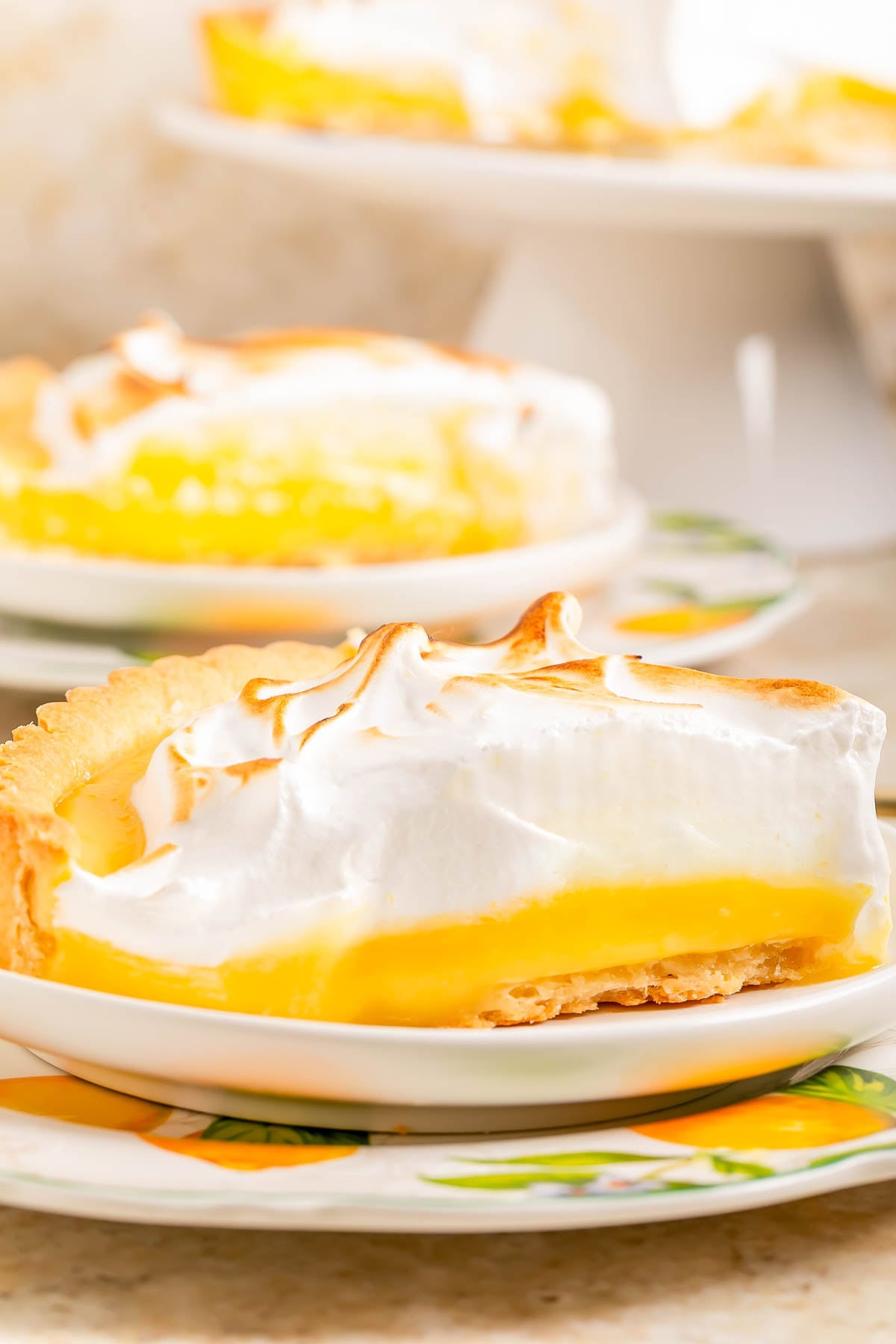 A slice of lemon meringue pie with a golden crust, yellow lemon filling, and toasted meringue topping on a plate.