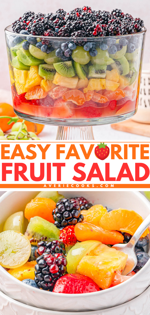 A clear trifle dish filled with layered fruit salad including strawberries, kiwi, oranges, grapes, blackberries, and blueberries; a serving shown in a bowl with a spoon.