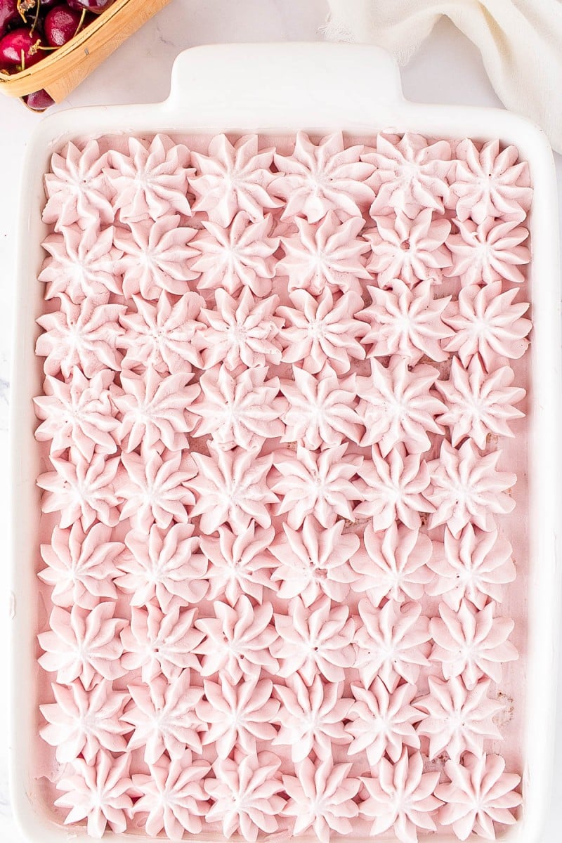 A white dish filled with neatly piped rows of pink star-shaped whipped topping, seen from above.