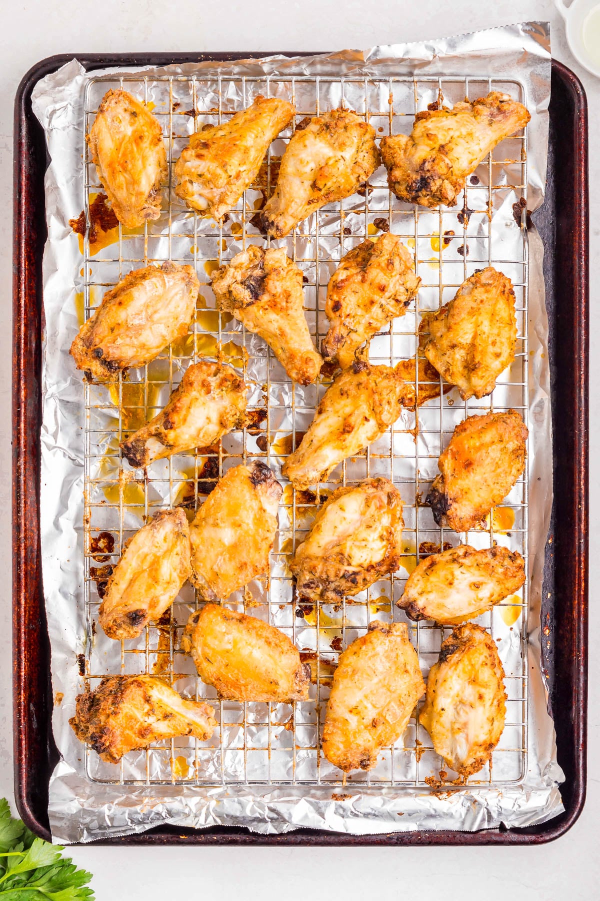 Chicken wings arranged on a wire rack over a foil-lined baking sheet, cooked and lightly browned.
