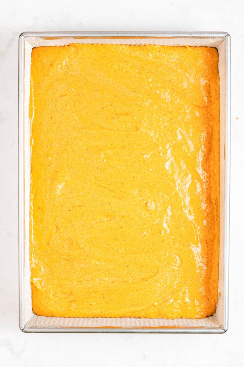 A rectangular metal baking pan filled with a smooth, evenly baked yellow cake with a slightly glossy surface.