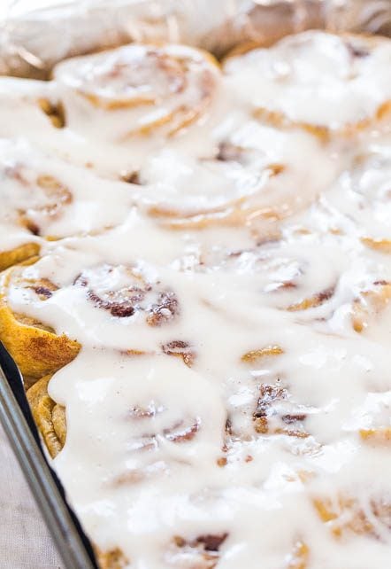 a pan of glazed pumpkin spice cinnamon rolls 