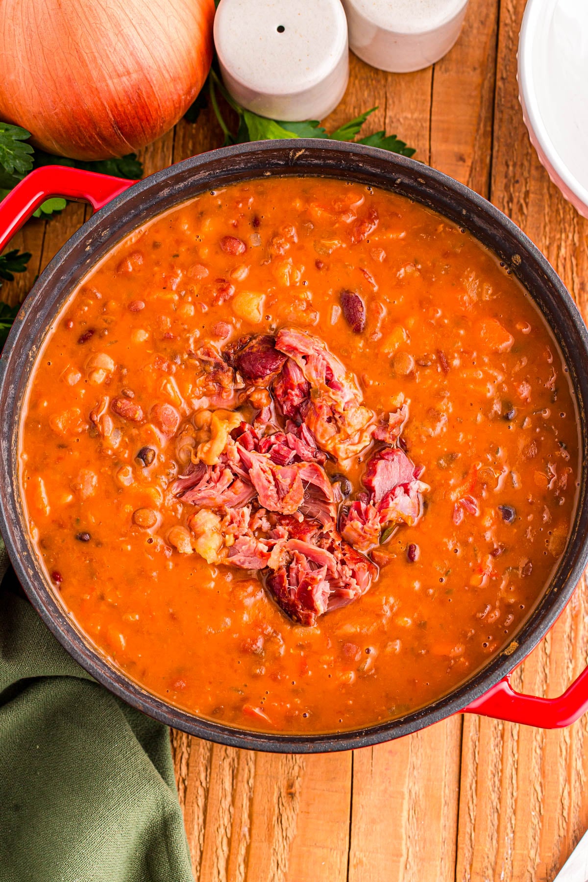 A pot of bean soup topped with shredded ham.