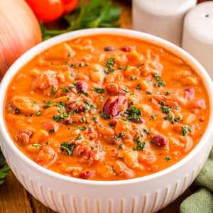 A bowl of creamy vegetable and bean soup topped with fresh herbs.