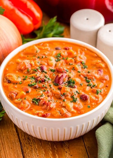 A bowl of creamy vegetable and bean soup topped with fresh herbs.