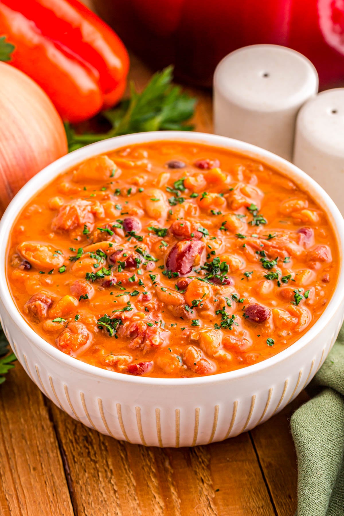 A bowl of creamy vegetable and bean soup topped with fresh herbs.