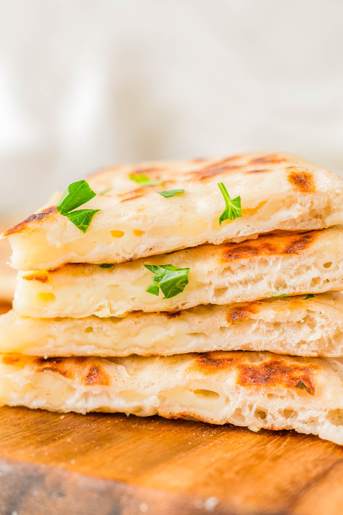 A stack of four slices of cheese-filled flatbread garnished with parsley.