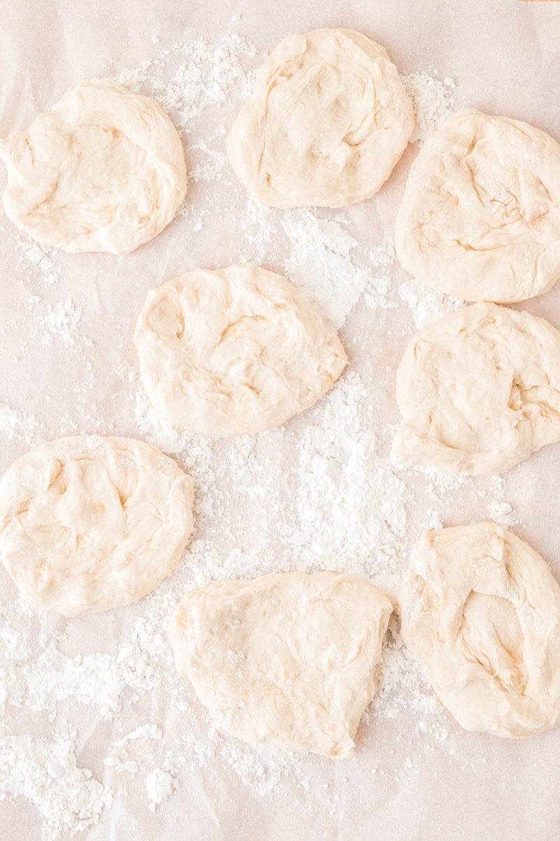 Eight portions of raw dough resting on a floured surface.