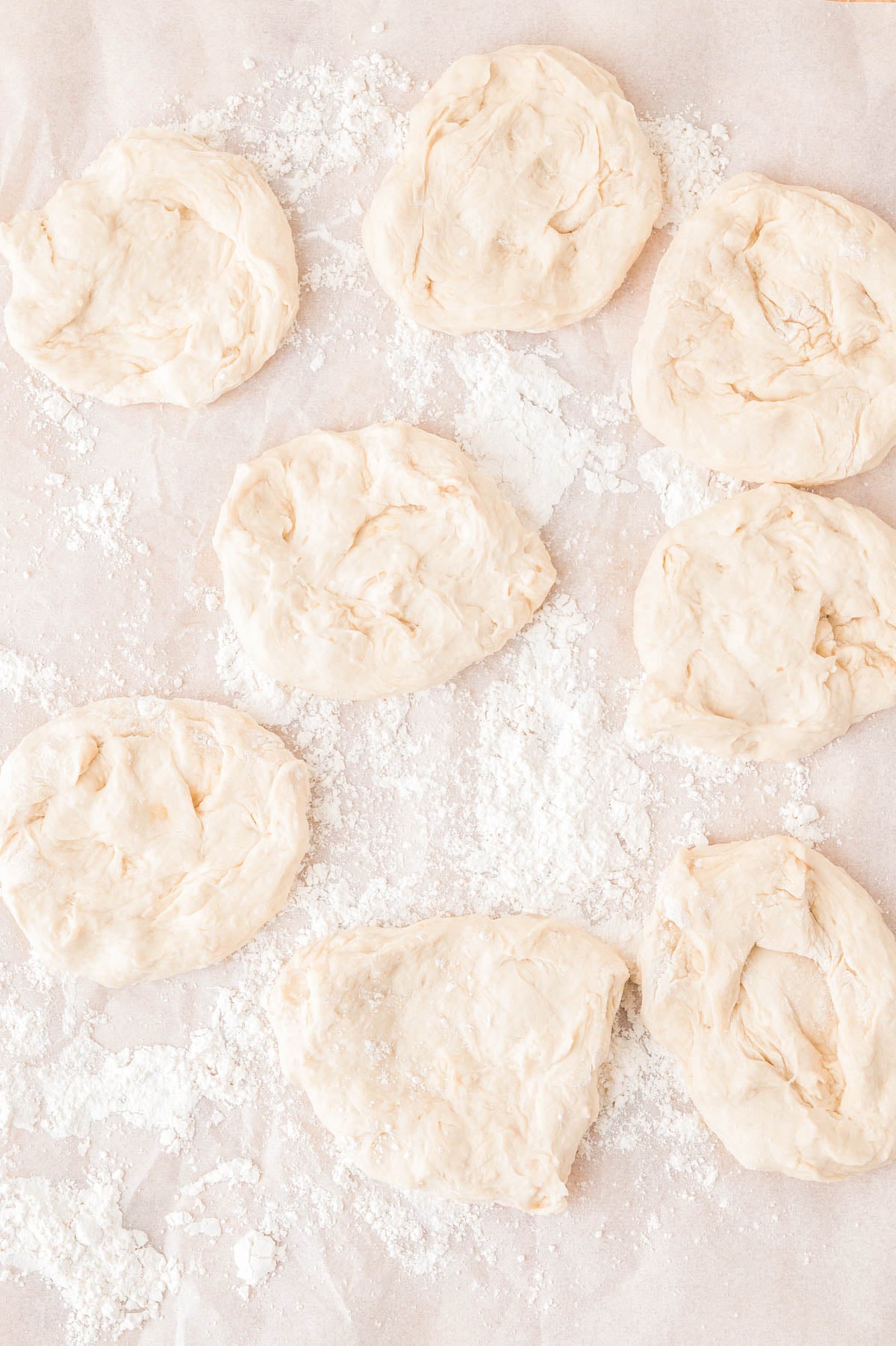 Eight portions of raw dough resting on a floured surface.