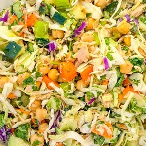 A salad of shredded cabbage, chickpeas, diced cucumber, carrots, and herbs.