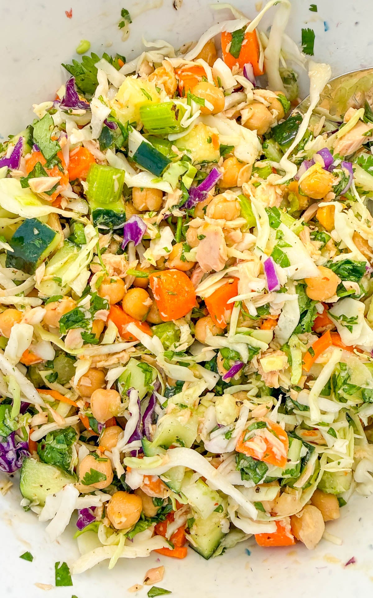 A salad of shredded cabbage, chickpeas, diced cucumber, carrots, and herbs.